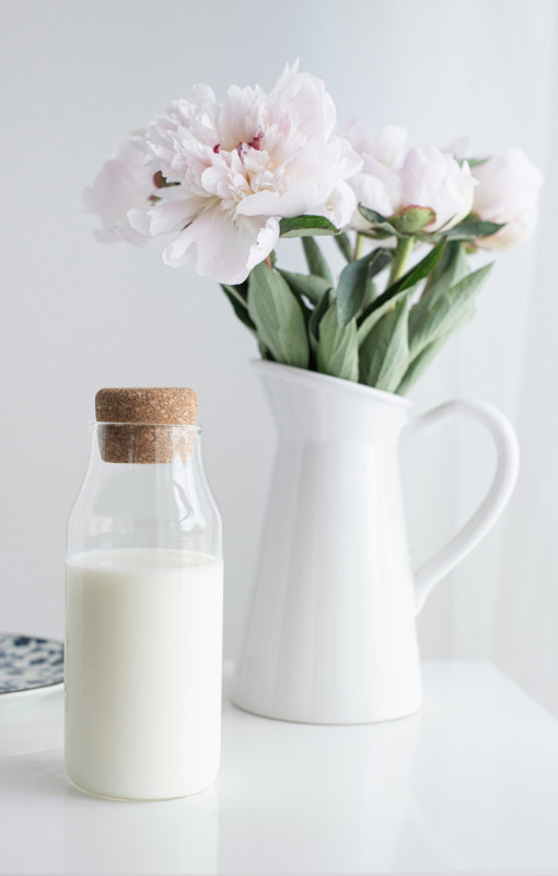 Glasflasche mit Milch und Blumenvase